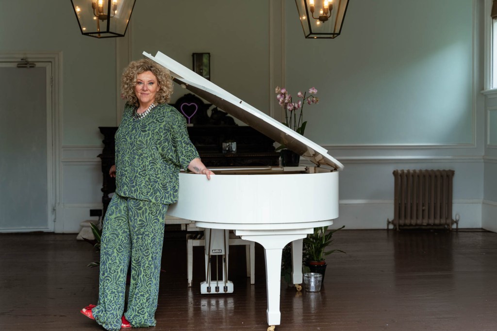 Cotswolds Wedding Pianist Emma, dressed in green, with a white grand piano.